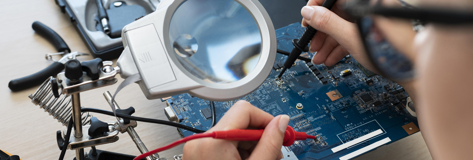 Equipe técnica da 100% Micro analisando placa-mãe em bancada de trabalho